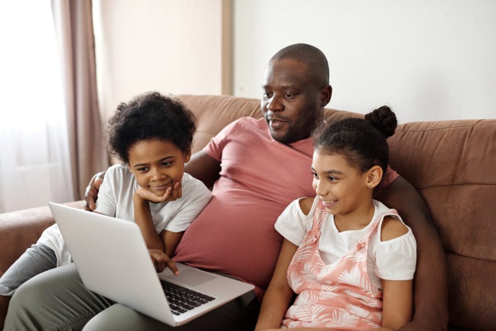 Father and children enjoying time together watching a laptop indoors.