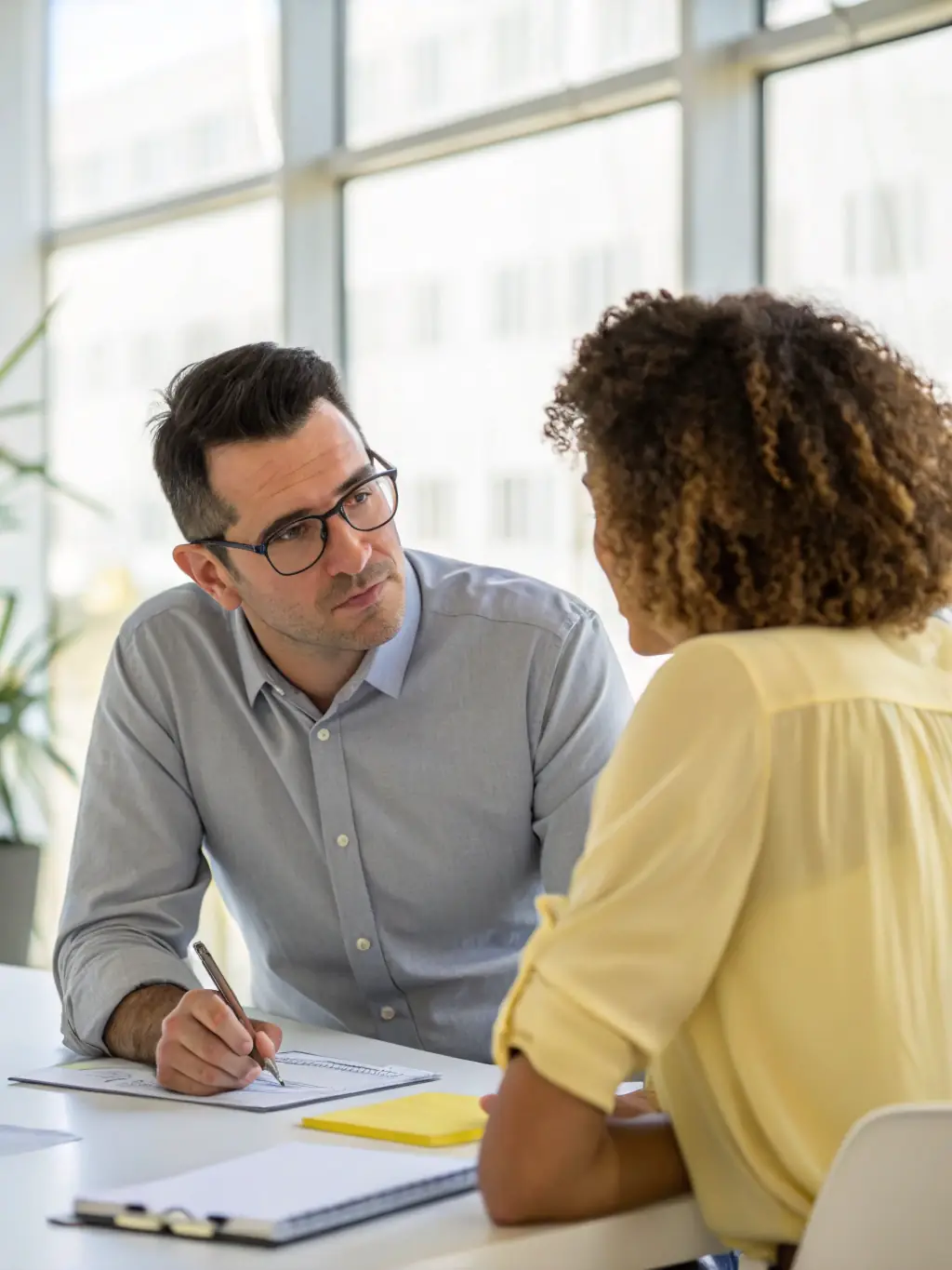 A mentor guiding a mentee in a modern office, representing 1:1 mentorship for up to 1 year.